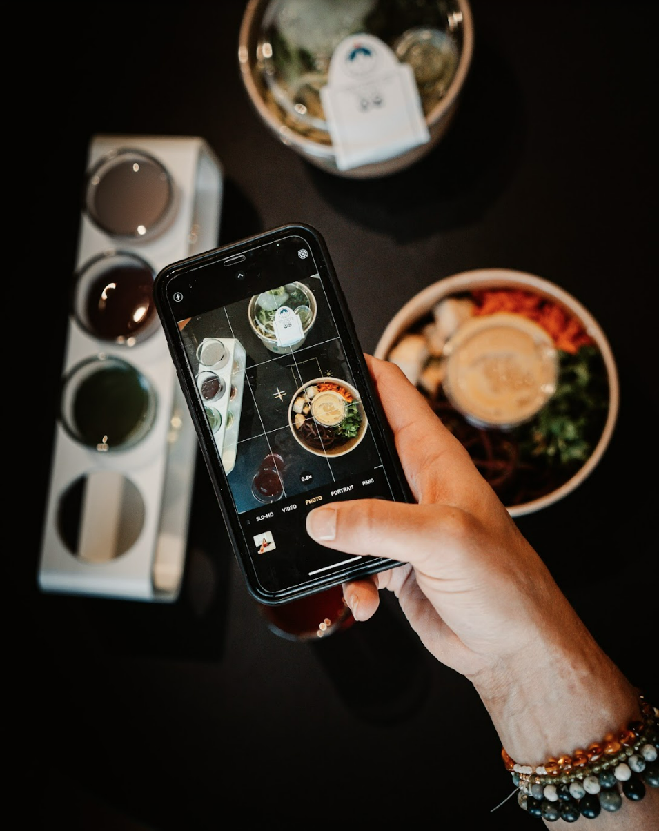 Motherlove ferments owner Rochelle Minagawa takes a photo of vegan bowls made by the wagon food truck, as well as flight of kombucha and water kefir